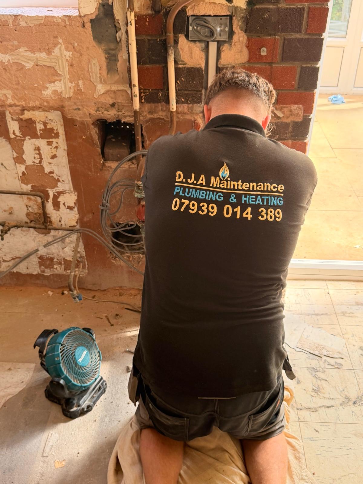 DJA Maintenance engineer working on heating pipework at an exposed brick wall