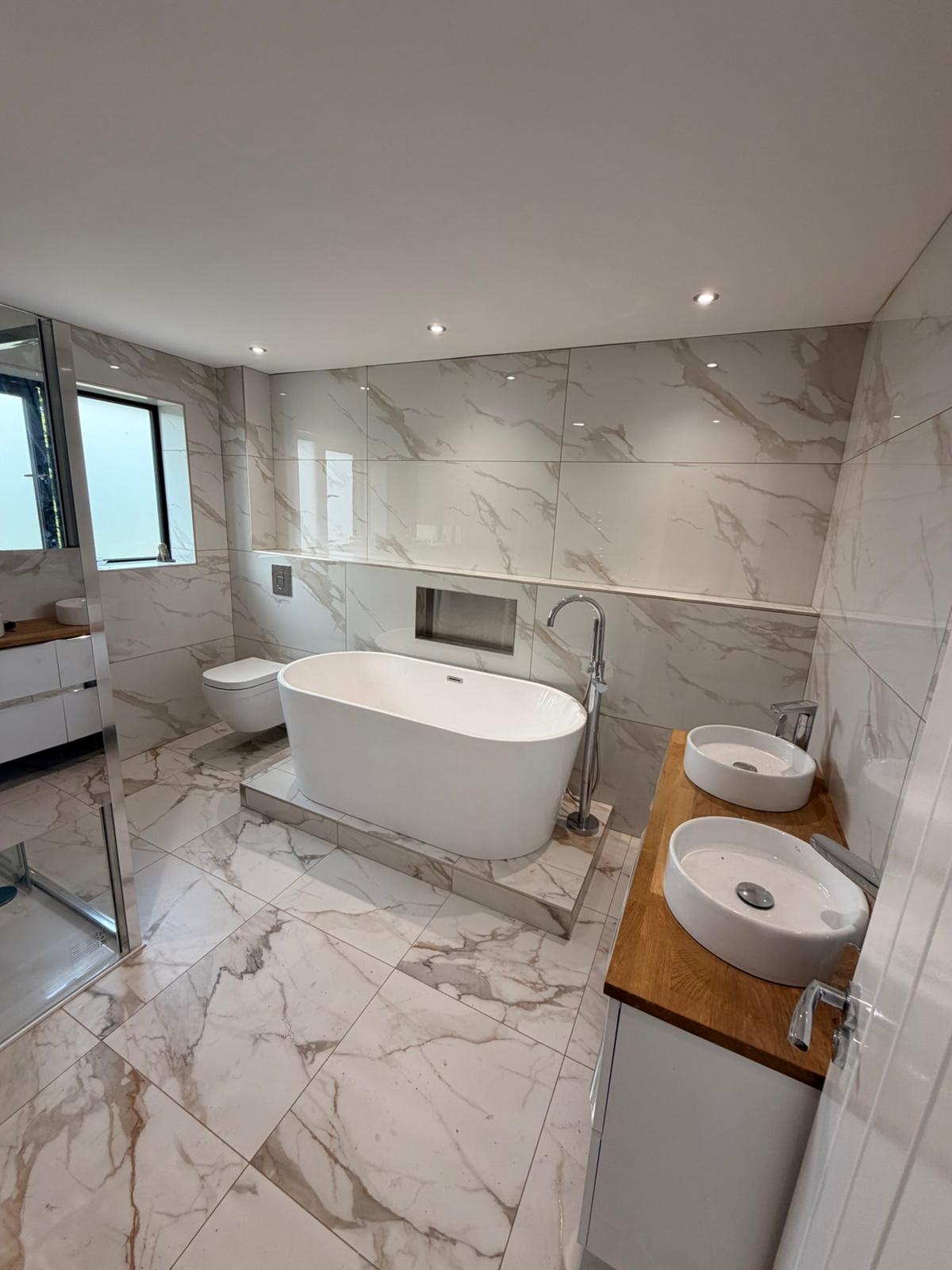 Finished marble-tiled bathroom with freestanding bath and twin basins